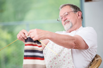 Senior man knitting at home