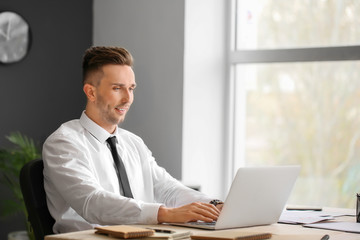 Young businessman working on laptop in office