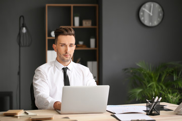 Young businessman working on laptop in office