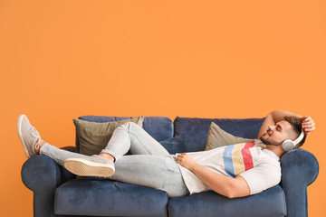 Young man listening to music while lying on sofa at home