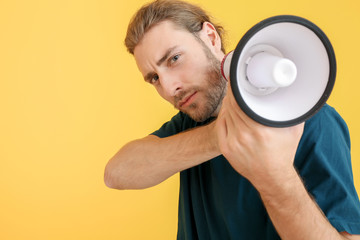 Young man with megaphone on color background