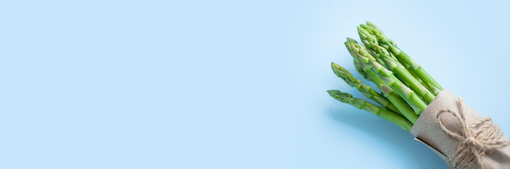 bunch of fresh green asparagus on a blue background, banner format