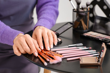 Female makeup artist with decorative cosmetics in beauty salon, closeup