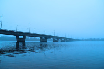 View of the bridge over the river in the fog. Cold morning
