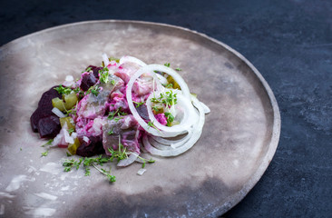 Traditional matie herring with beetroot salad and onion rings offered as closeup on a rustic modern...