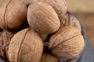 group of fresh raw walnuts in clay pot on grunge wooden background. rustic and detailed image. closeup.