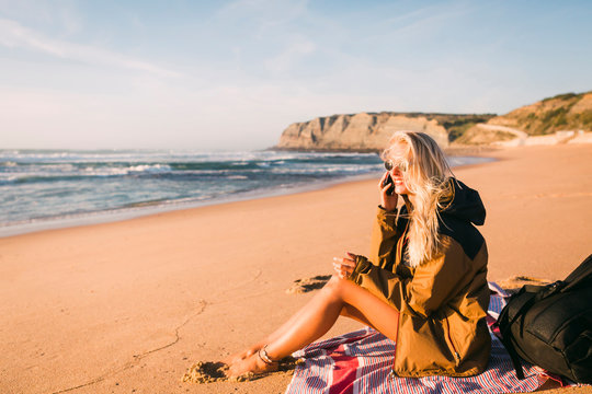 Smiling woman talking on phone sitting on beach