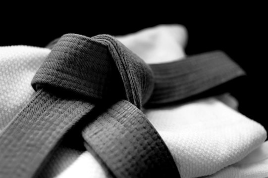 Black judo, aikido or karate belt on white budo gi. Concept is applicable to sports, business or education