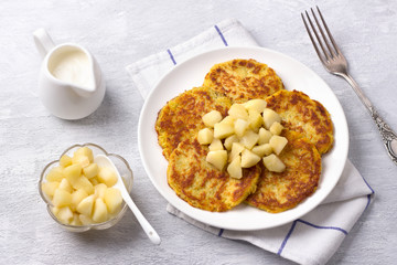 Traditional latkes fritters with sour cream and apple sauce on light gray textured background	
