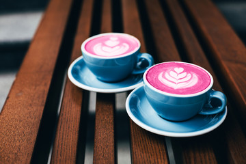 Two trendy beetroot lattes with latte art and flower petals on the foam.