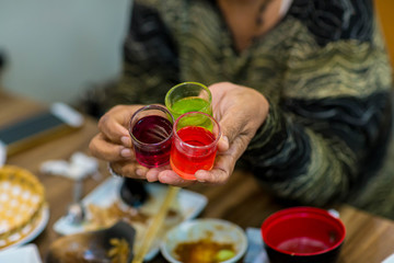 Fototapeta na wymiar Dessert glass cup of colorful jelly served on hand woman. colored fruit jelly in glass cup . Eating colorful striped jelly or jello on hand. Multi Color fruit jelly in the glass cups.