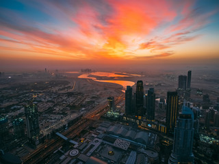 Naklejka na ściany i meble Beautiful sunrise above Dubai skyline, United Arab Emirates, aerial panoramic view from rooftop of skyscraper.