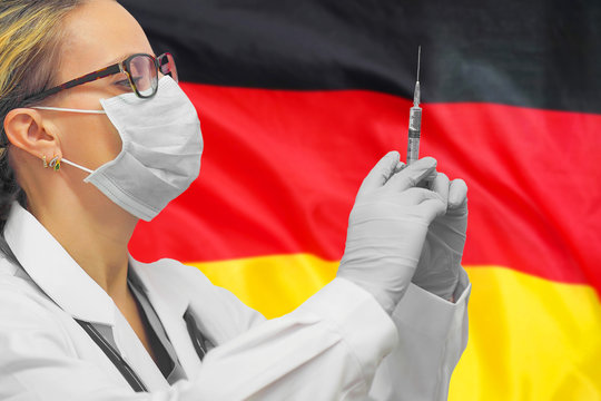 Female doctor or nurse in gloves holding syringe for vaccination against the background of the Germany flag. Medicine concept and fight the virus. Coronavirus in Germany.
