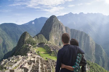 Cercles muraux Machu Picchu Young couple embracing contemplating the incredible landscape of Machu Picchu. The ruins of the citadel of Machu Picchu and Mount Huayna Picchu are seen
