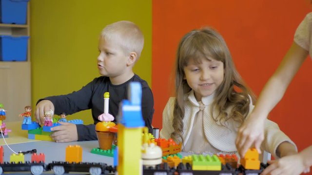 Children in the classroom make figures with teacher. Modern technology concept