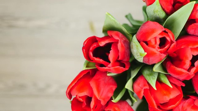 Top View Rotating Of Beautiful Bouquet Red Tulips In Vase Standing On A Gray Wooden Background On The Right Side Close-up.