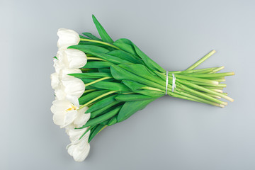 bouquet of white tulips on a gray background. spring flowers. a bouquet of flowers for the holiday close-up top view. natural background