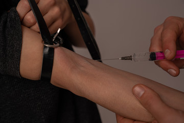 Close up photo, young couple injecting heroin into a vein with syringe. Narcotic recreational drugs...