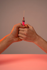 Male hand and female hand holdin together syringe, isolated over grey background