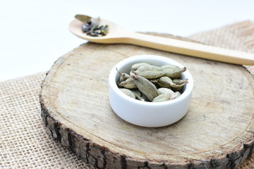 Dry cardamom seed (Elettaria cardamomum) displayed in containers and spoons