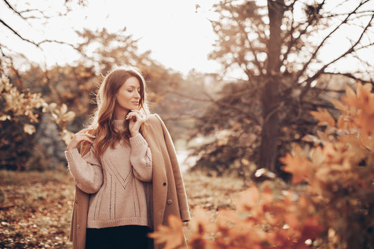 Beautiful girl in autumn park . young woman in a warm cashmere coat walks in the park at sunset in autumn. 