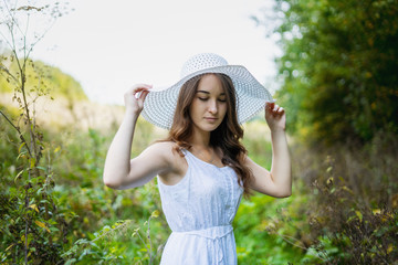 Beautiful girl in a white dress. Woman in a summer park. Beautiful long-haired girl in a...