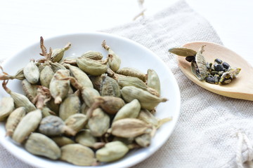 Dry cardamom seed (Elettaria cardamomum) displayed in containers and spoons