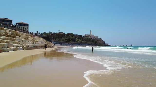 Tel Aviv-Yafo Jaffa beach with people bathing in sunny daytime, camera panning onto Mediterranean Sea,, 4k video footage
