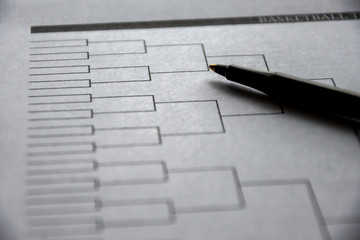 Blank basketball bracket grid on white paper with pen laying on top - Powered by Adobe