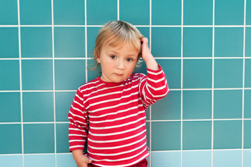 Portrait of adorable toddler boy scratching the head