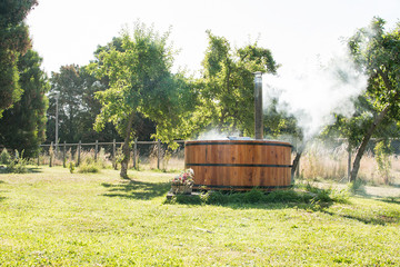 Wooden bathtub in the garden of my house with a fireplace to burn wood and heat water, that's why the smoke comes out