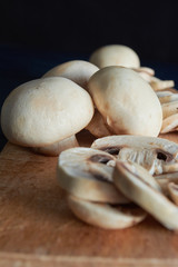 whole and sliced ​​mushrooms, on wooden board, on blue background