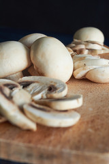 whole and sliced ​​mushrooms, on wooden board, on blue background