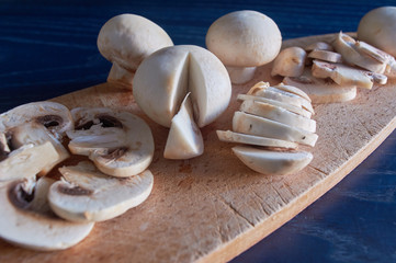 whole and sliced ​​mushrooms, on wooden board, on blue background