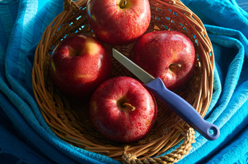 red apples in hand made basket with blue background