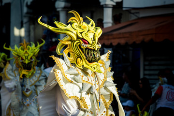 persons in shiny masquerade costumes pass by city street at dominican carnival