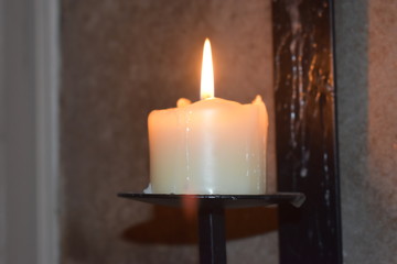 Bright light from white candle burning against a wall background