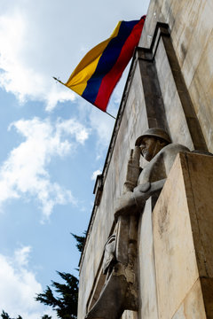 Two Stone Soldiers guard the Military Mausoleum in Cementerio Central. Colombian flag waving at background
