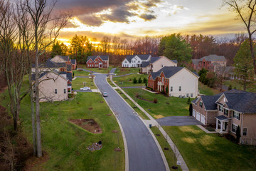 Aerial sunset view of an American  dead end,  cul-de-sac, no through street or no exit road, with luxury single family houses brick, stone, vinyl siding or facade and decorative entrances with columns