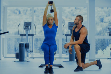 Obraz premium Fitness instructor with girl on training in fitness center