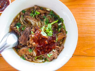 Beef noodles on orange wood floor.
