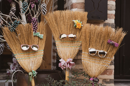 Decorative broom sticks wearing a sunglasses and flowers head pin and necktie.