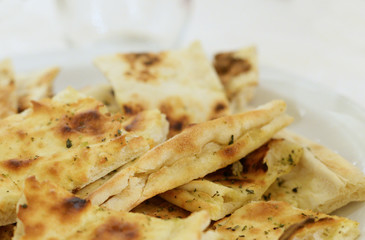 White plate with toasted Italian bread or crostini, sprinkled with olive oil and herbs. Selective focus