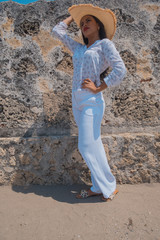 A young woman in white pants with an old wall behind her. Vintage feel.
