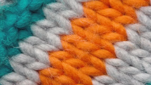Fibers of knitted clothes with multi-colored threads. Knitted fabric threads macro. Pan to right