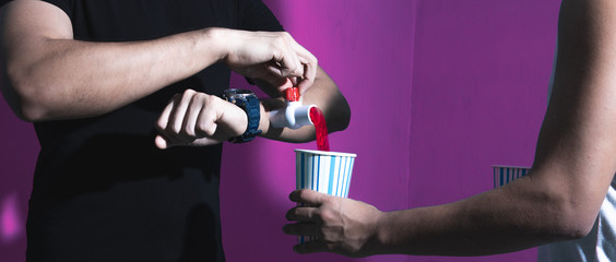 One man drinking another man's blood in a contrasty purple background. Concept of someone elses...