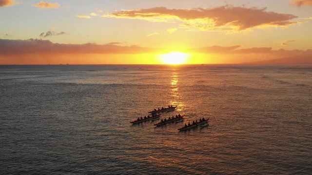 A professional drone orbits a group of kayak racers in Hawaii as the sun sets behind them. Beauty meets passion meets sport meets competition meets relaxation.
