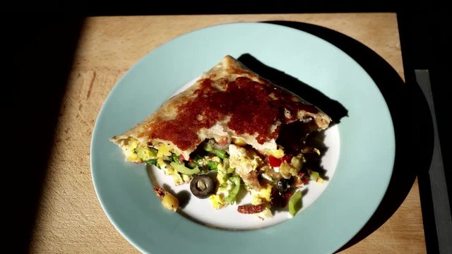 Zoom to pocket pizza calzone on wooden background. Comfort food.