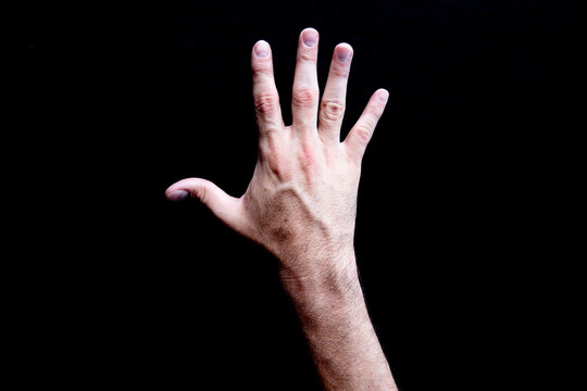 Open white adult male veiny hand with palm facing down on a black background 