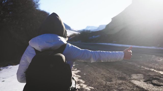Tourist girl with a large backpack hitchhiking on a lonely rural road. Journey autostopem alone.